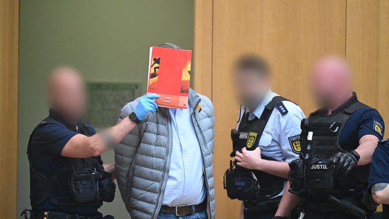 Ein Angeklagter wird in Stuttgart-Stammheim beim Beginn eines Prozesses um Reichsbürger in den Gerichtssaal geführt.