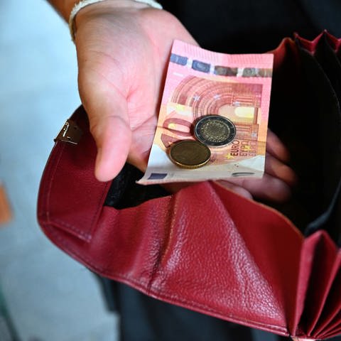 Ein Kellner eines Restaurants hält einen Geldbeutel in der Hand, während er in der anderen Hand Geld hält. (Foto: dpa Bildfunk, picture alliance/dpa | Felix Hörhager)